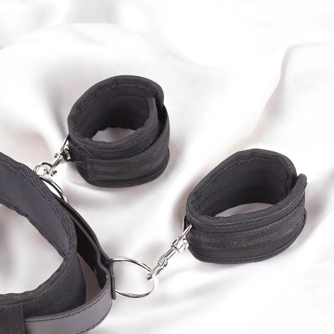 A pair of black bondage restraining straps with adjustable buckles and padding.