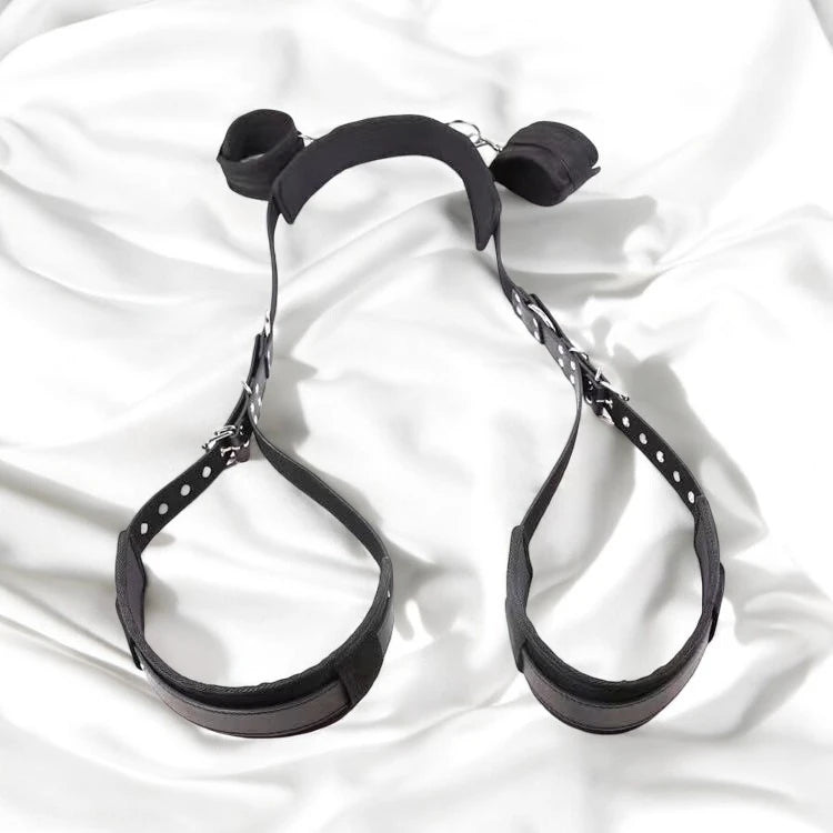A pair of black bondage restraining straps with adjustable buckles and padding.