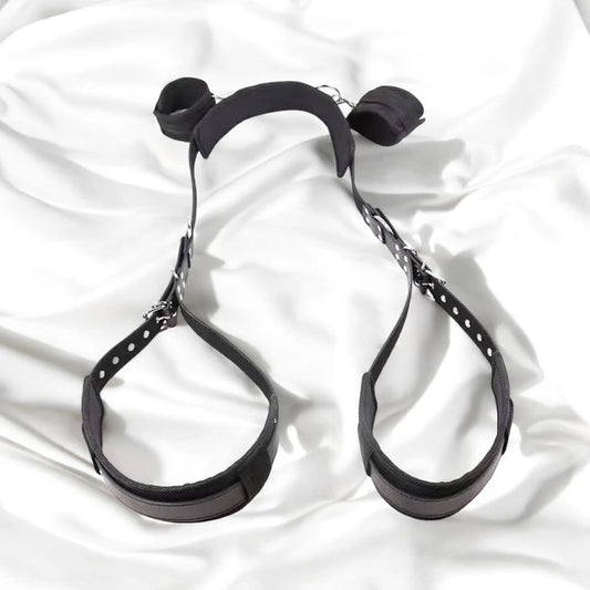 A pair of black bondage restraining straps with adjustable buckles and padding.